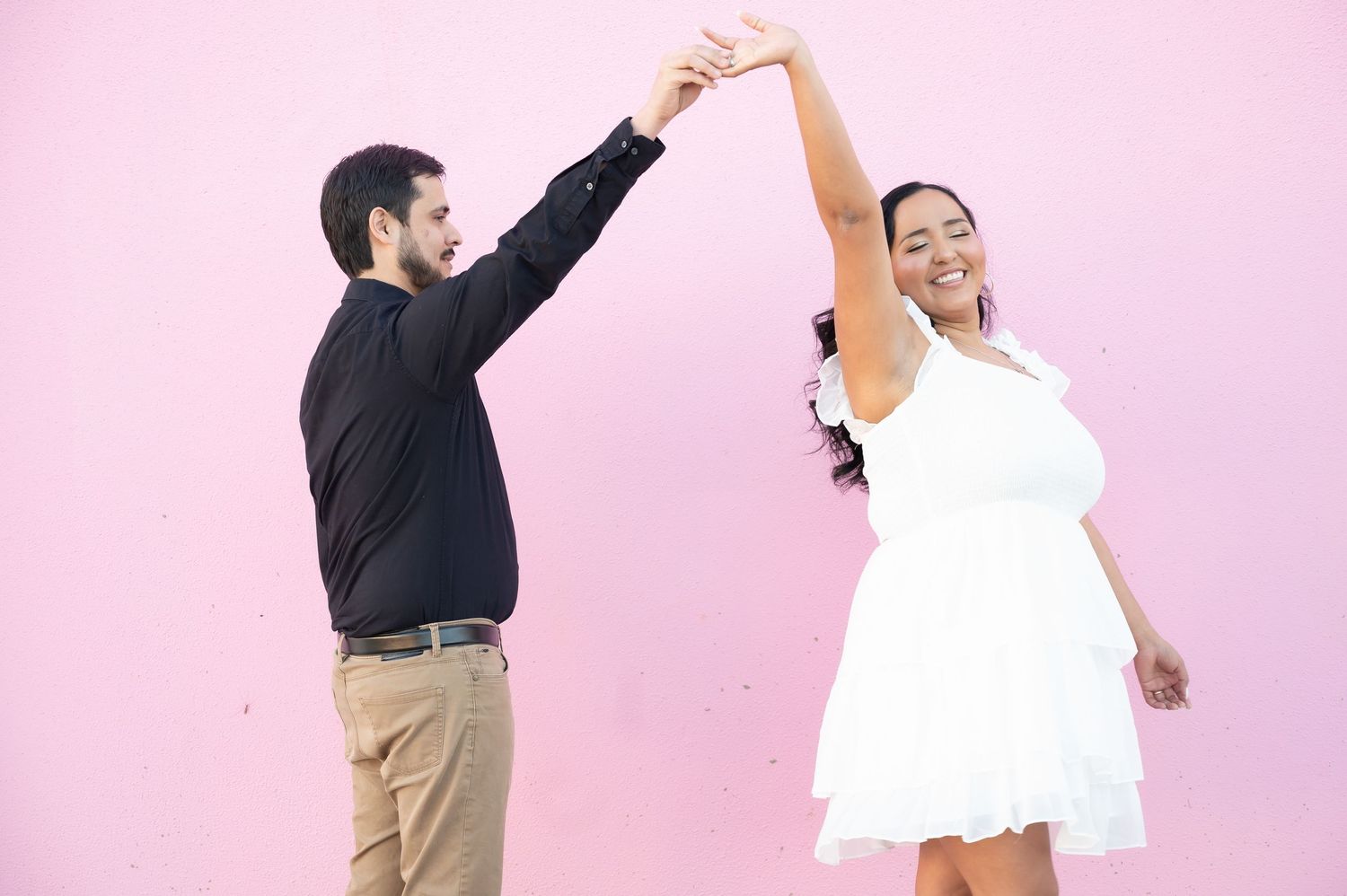 Two people perform a fun dance move in coordinated black and white outfits.