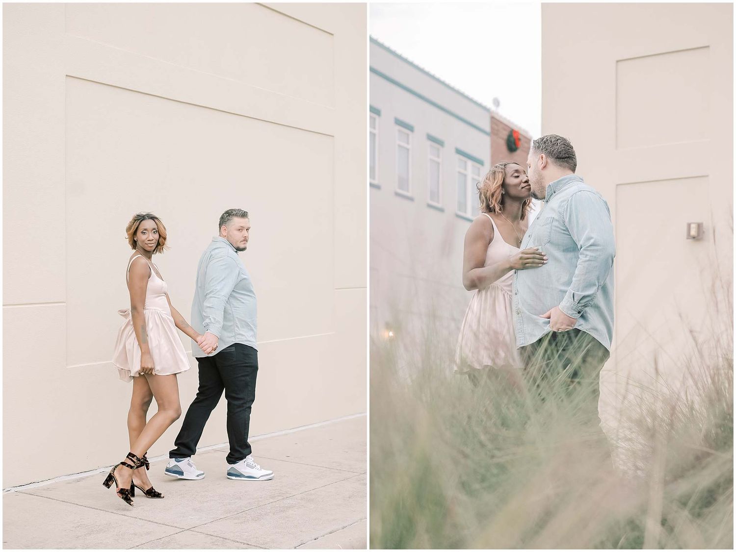 A couple poses playfully against a light colored wall wearing a pink dress and light blue shirt.