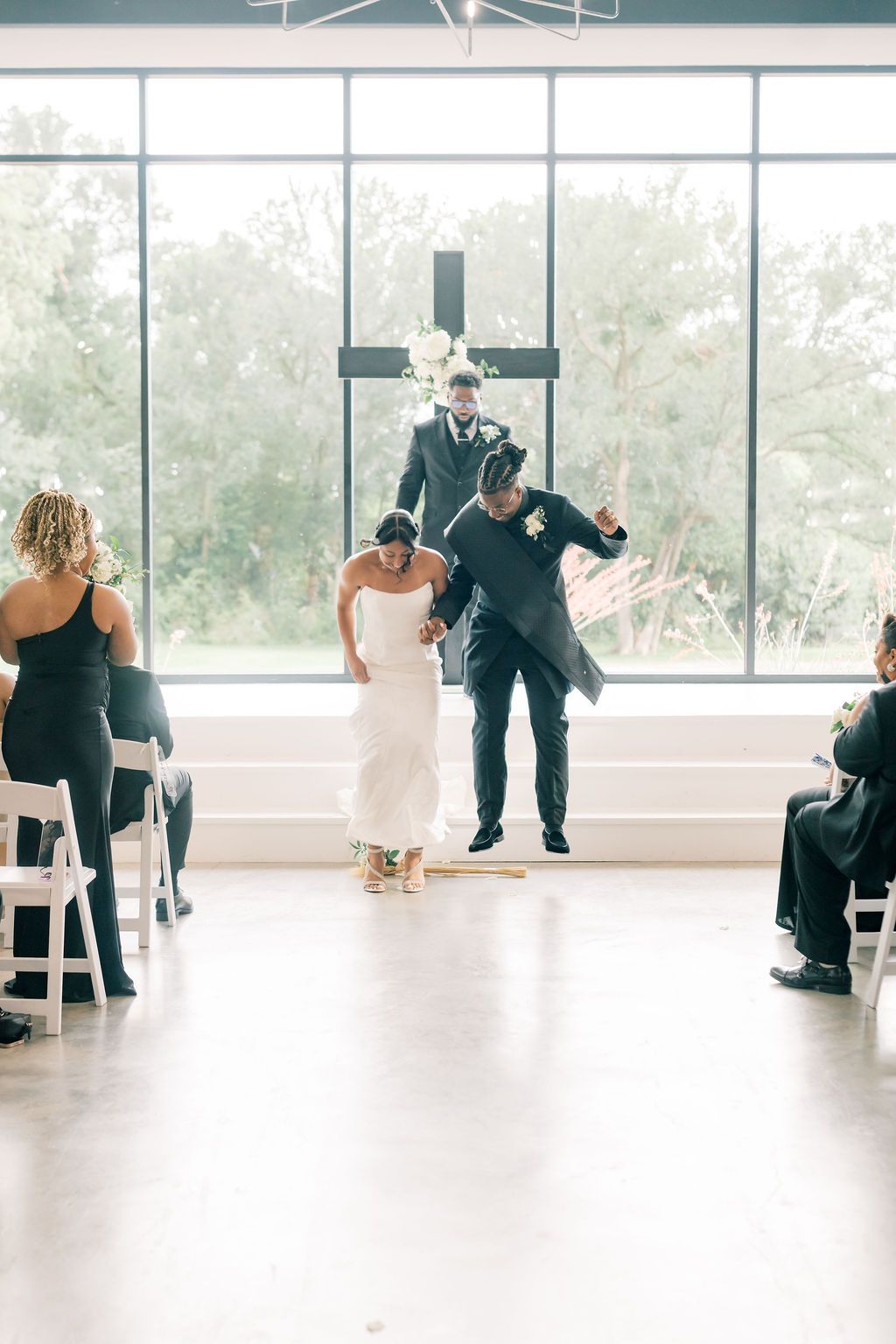 Bride and groom celebrate walking down the aisle after wedding ceremony in bright modern chapel with large windows.
