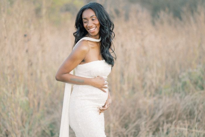 Artistic maternity portraits captured in a serene outdoor setting with soft lighting and white dress.