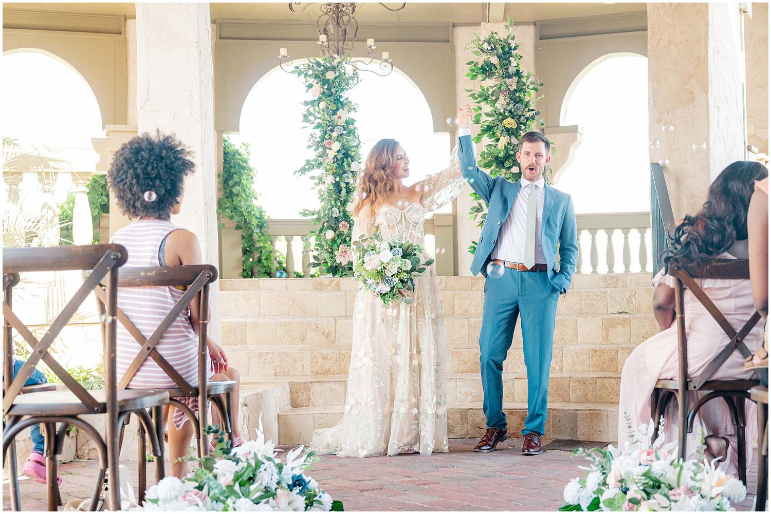 Stone archway venue with wooden chairs and greenery decorations set up for an elegant outdoor event.
