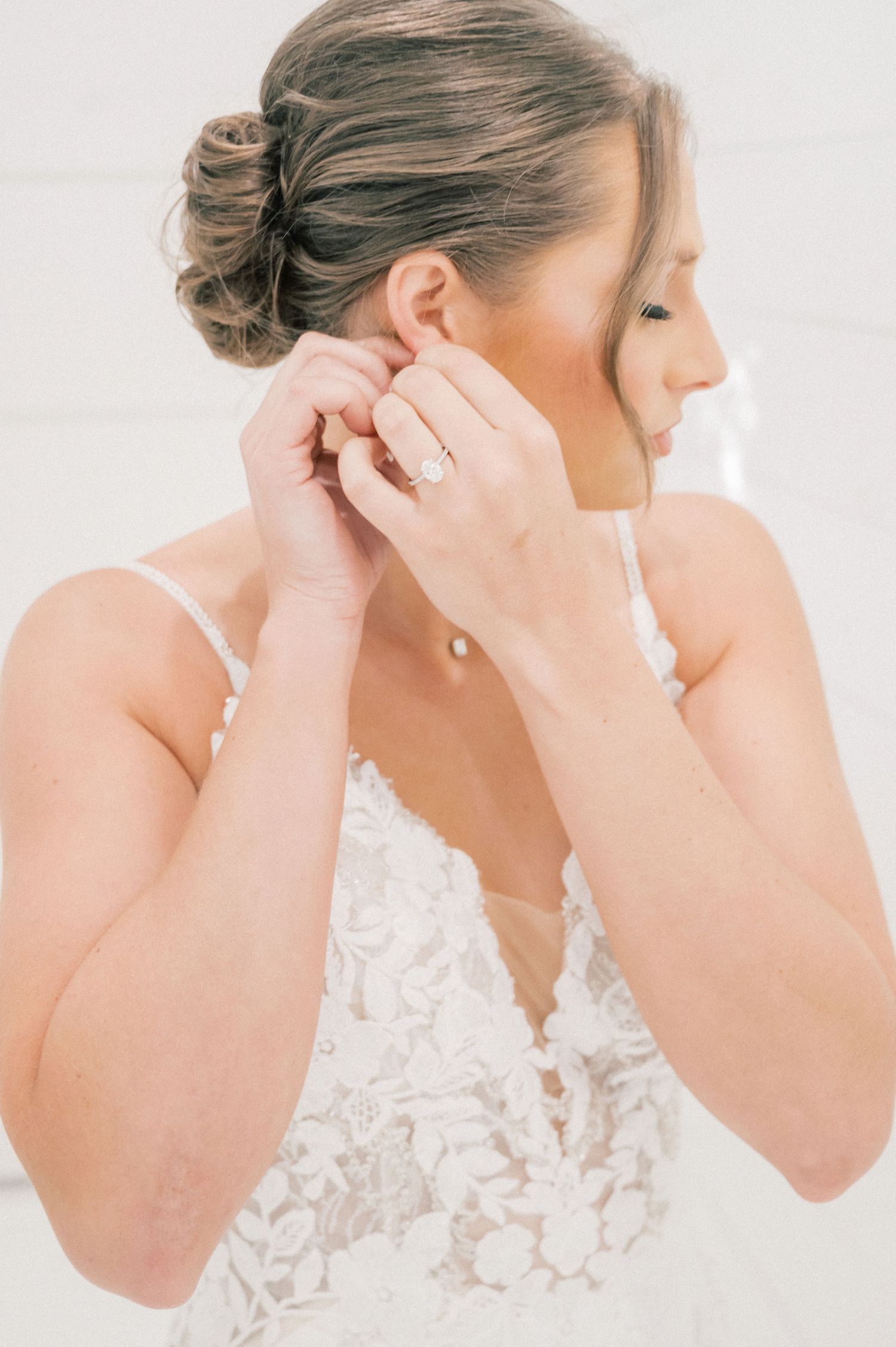 Side profile shots of a bride adjusting her earrings while wearing an elegant lace wedding gown.