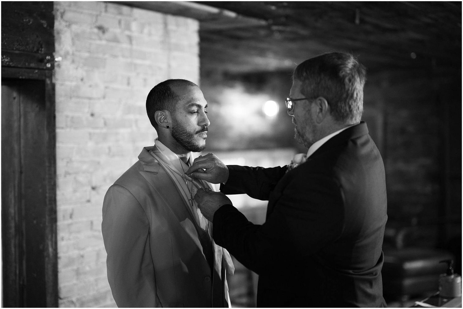 Interior wedding preparation scene in black and white at brick-walled venue.
