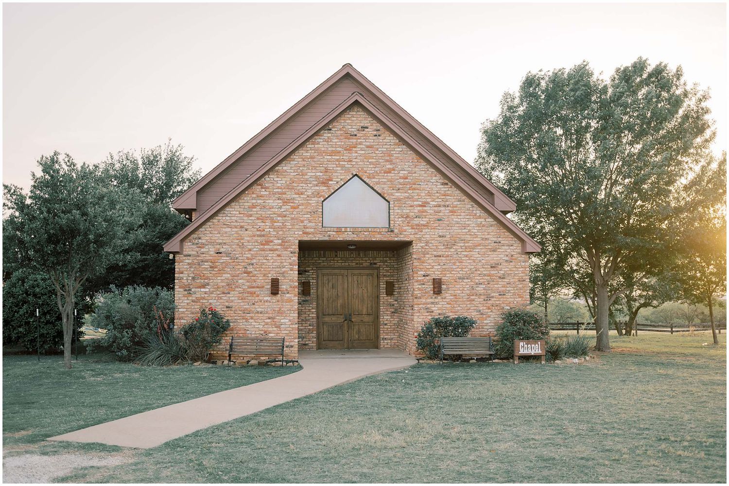 Brick chapel exterior with large windows photographed during golden hour.