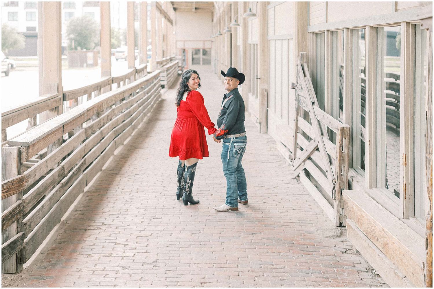 Two people walk and pose together in a modern concrete corridor with natural lighting.