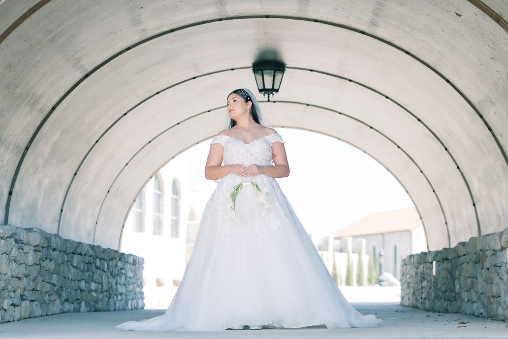 Wedding photography under a stone archway tunnel showcasing a flowing white ballgown dress.