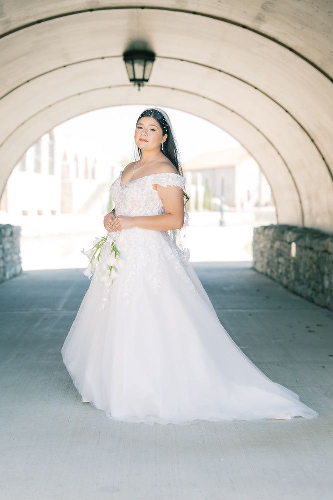 A bride in a flowing white wedding gown poses gracefully under a stone archway in a series of romantic portraits.