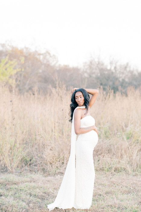 Ethereal outdoor photoshoot featuring a person in a flowing white dress against a natural field backdrop.