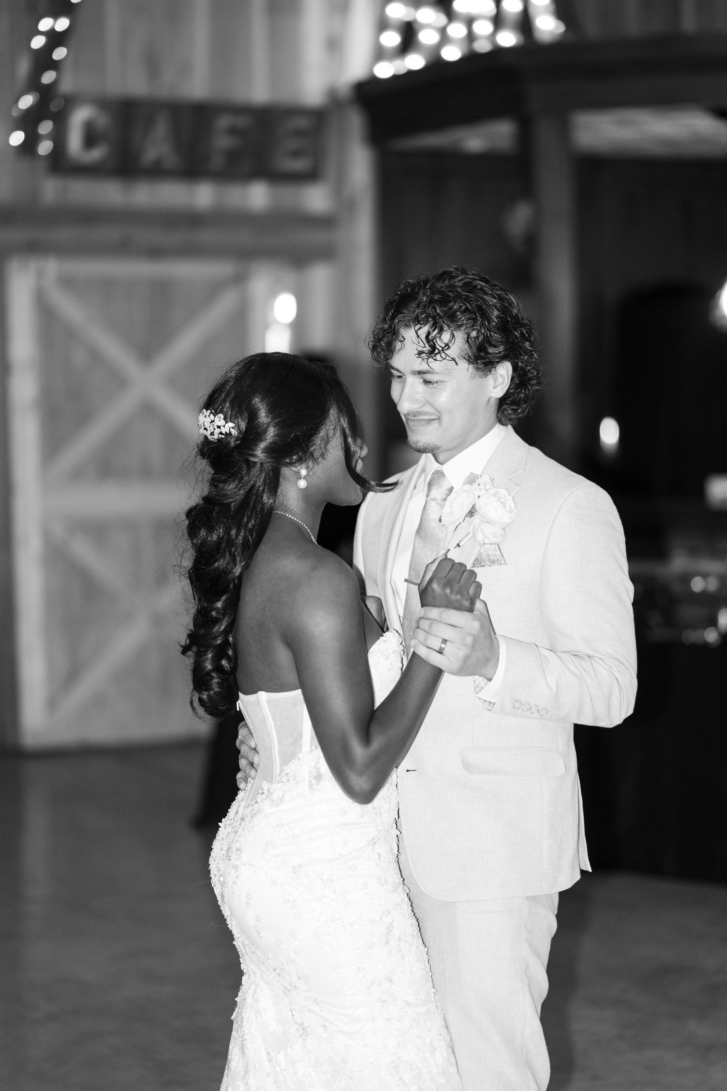 Bride and groom share first dance in barn venue, black and white wedding reception photo.