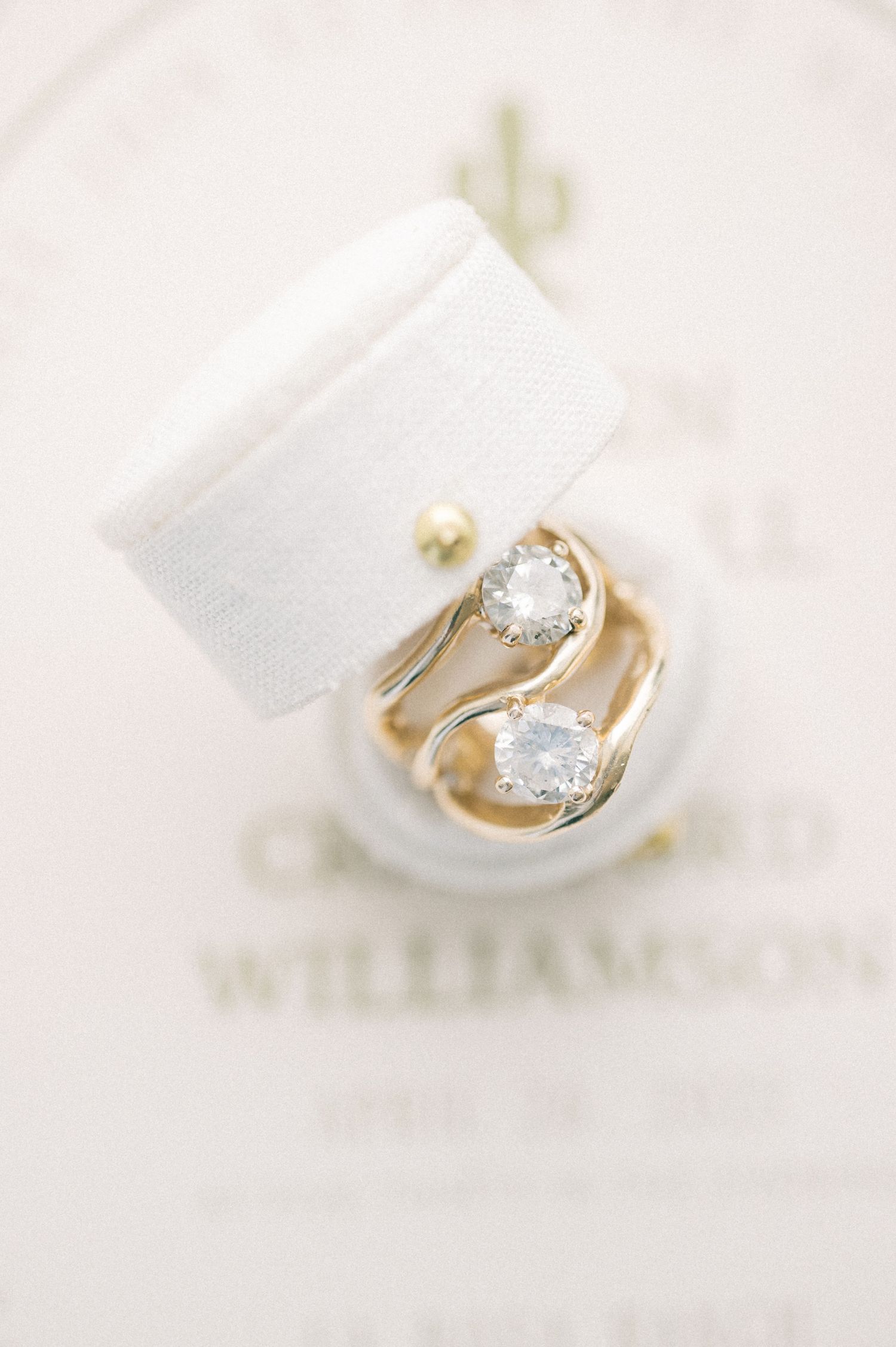 Elegant gold and diamond engagement ring nestled in white fabric.