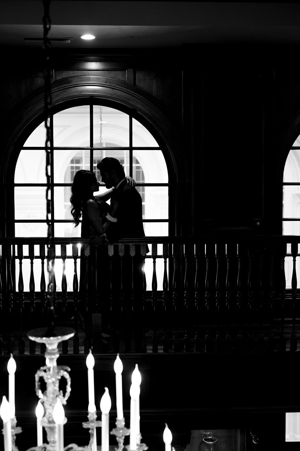Silhouetted figures against arched windows with glowing candelabras in foreground.