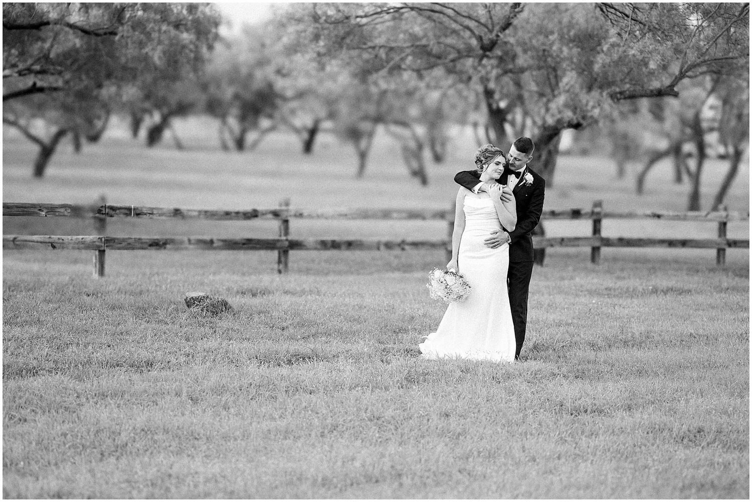 Black and white wedding photos showing romantic moments in a countryside setting with wooden fencing.