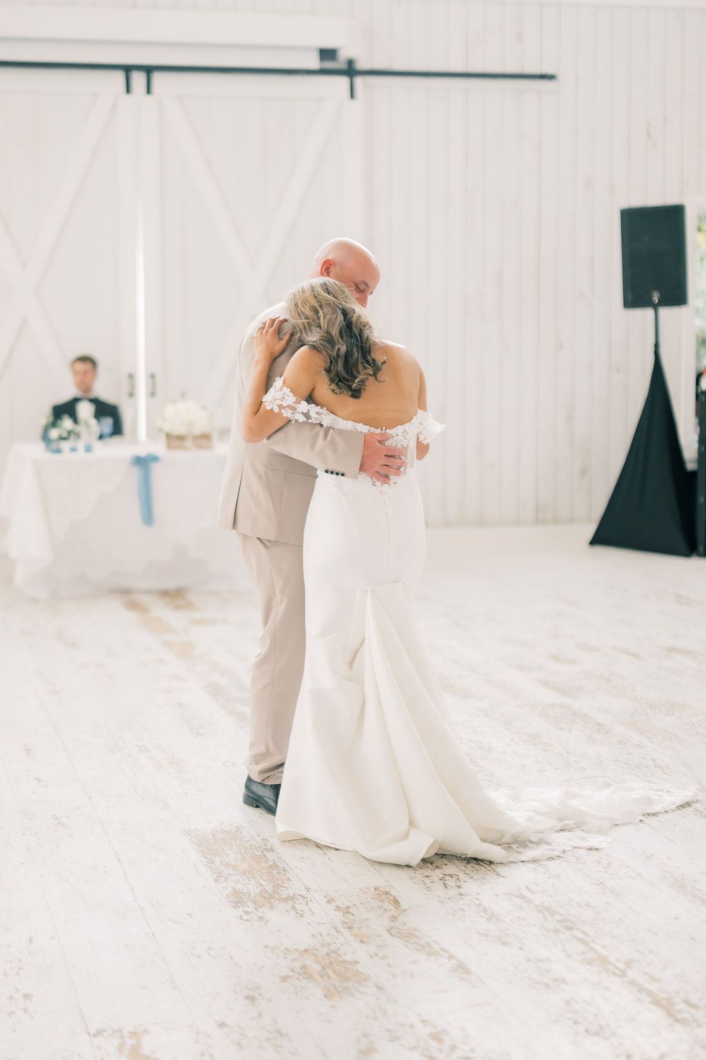Bride and father share emotional first dance in rustic white barn wedding reception venue.