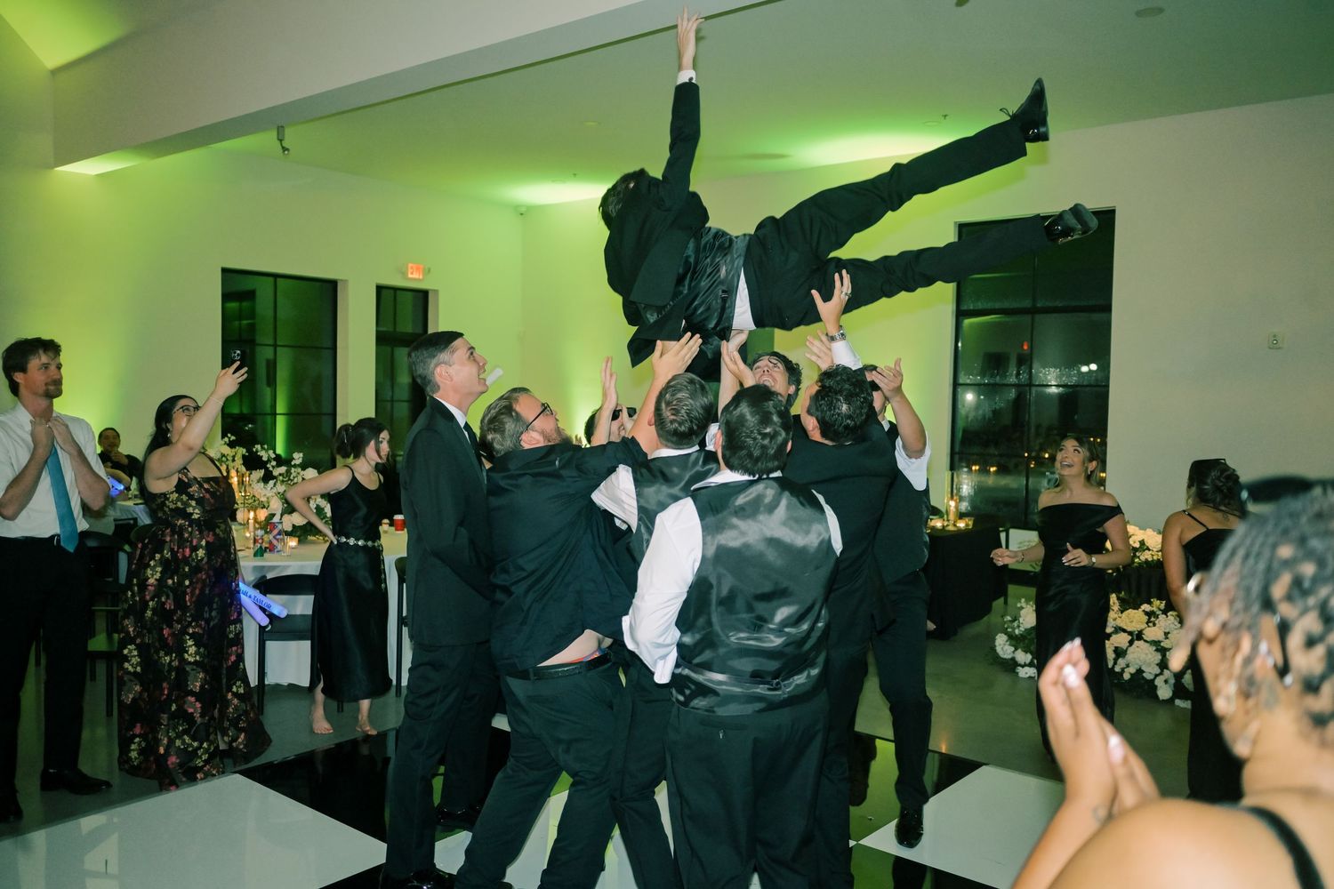 Groomsmen lifting groom in the air on the wedding reception dance floor.