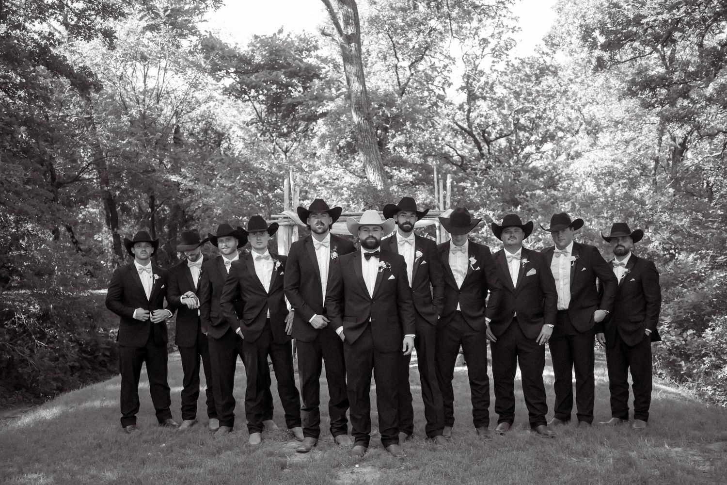 Black and white photo of groom and groomsmen in black suits and cowboy hats.