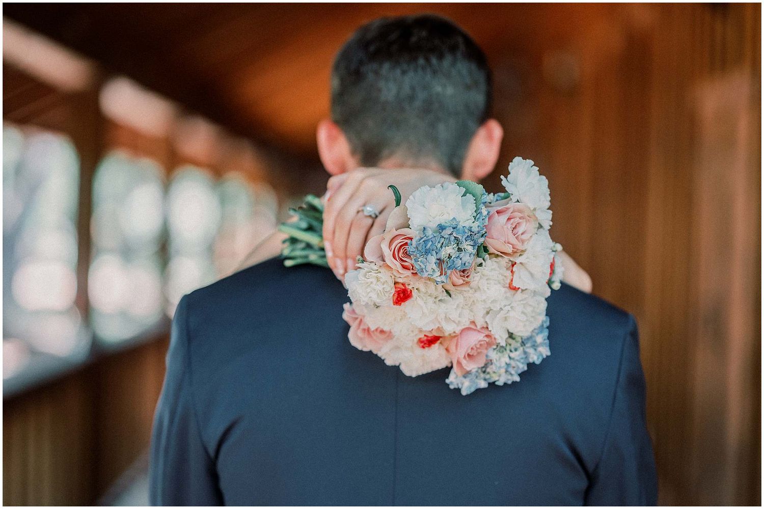 Wedding party wearing dusty blue dresses and suits adorned with pink and blue floral bouquets and boutonnieres.