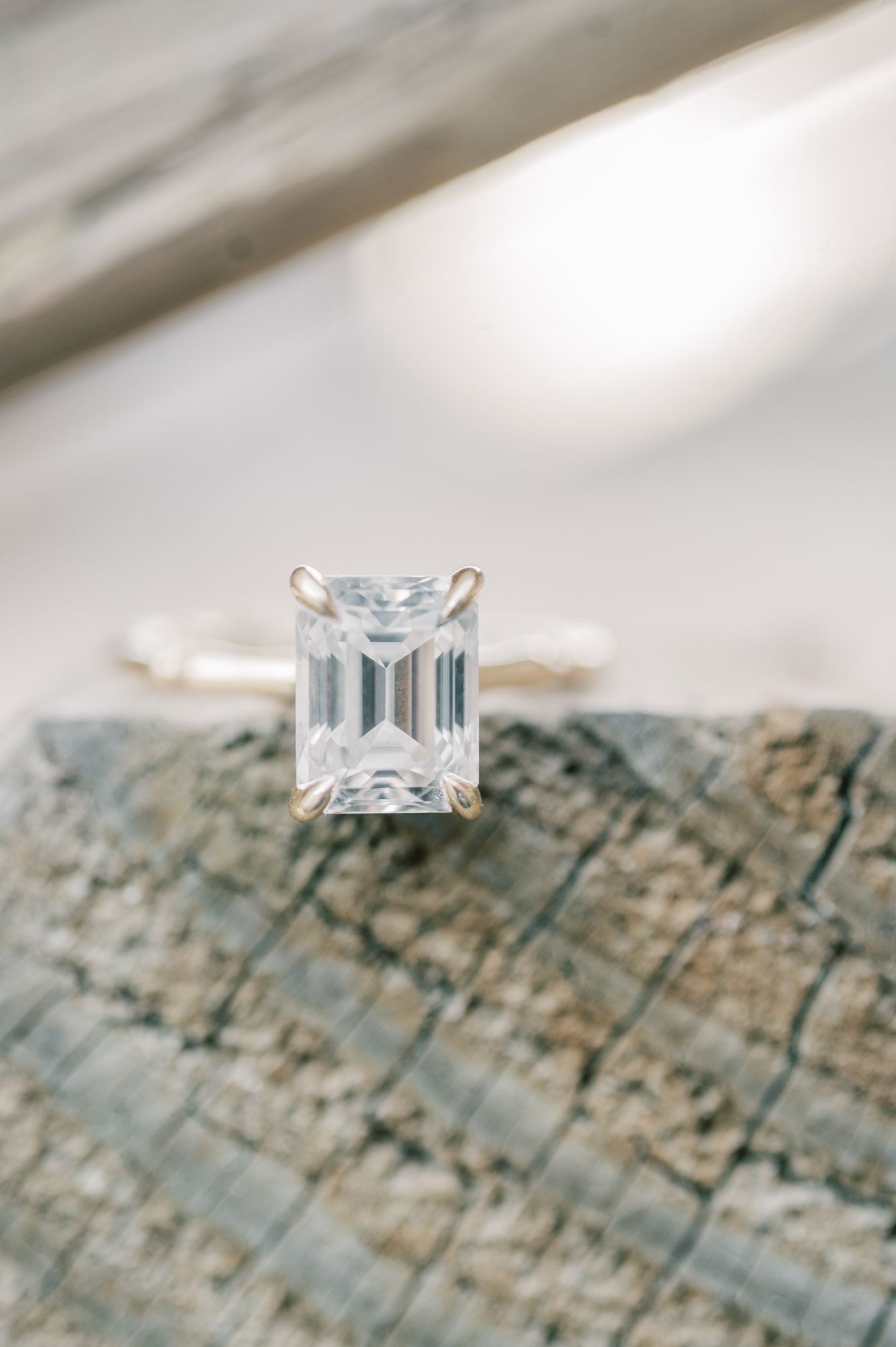 Princess cut diamond ring on a gold band photographed against weathered wood texture.