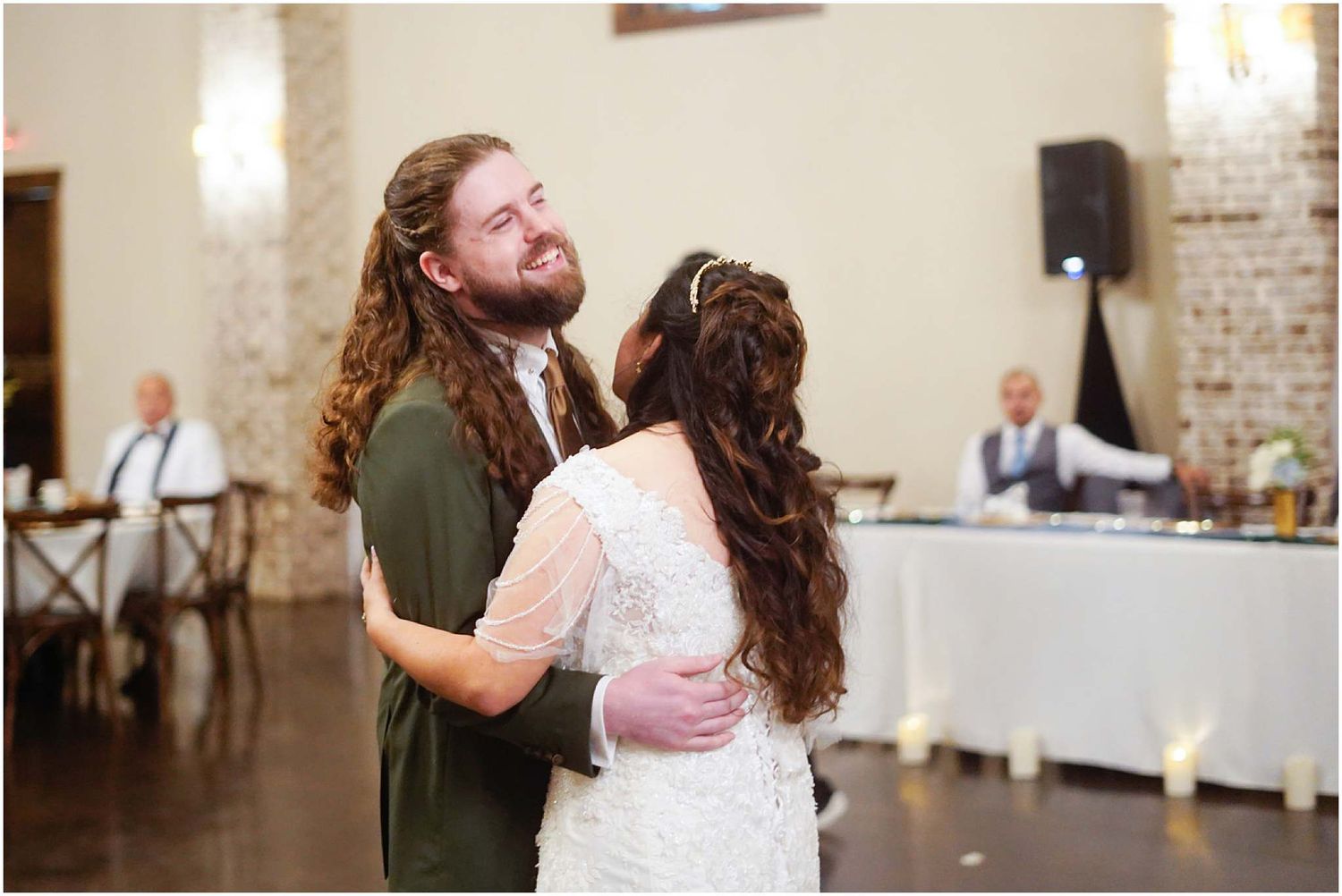 Bride and groom share their first dance at a rustic wedding reception venue with exposed brick walls.