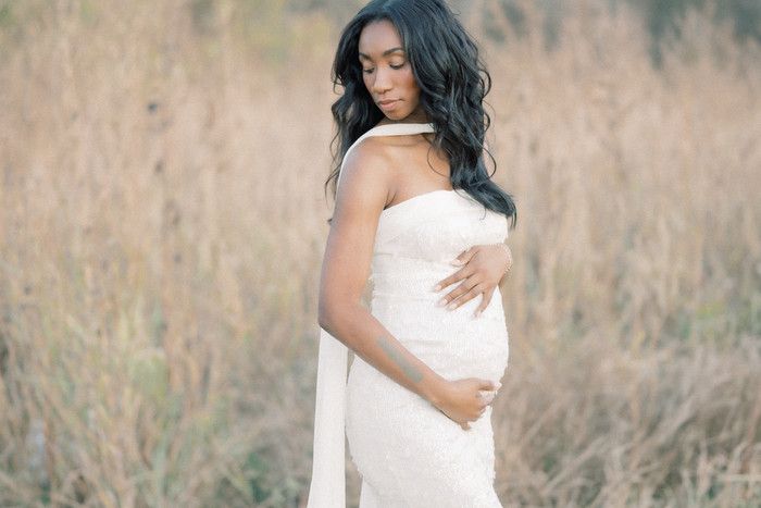 Serene outdoor maternity photography with white gown and natural lighting.