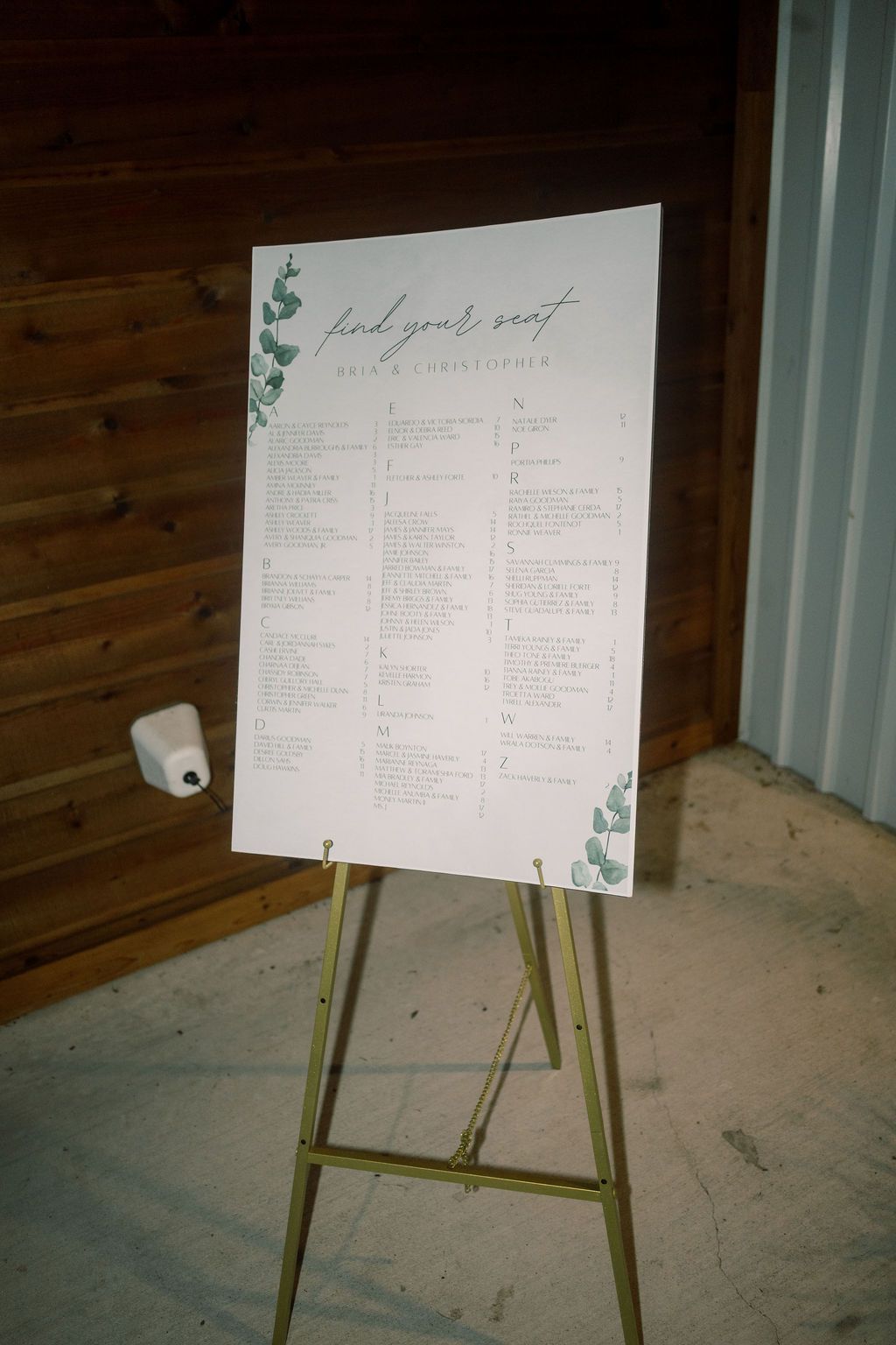 Elegant wedding seating chart on gold easel with eucalyptus accents and cursive find your seat lettering.