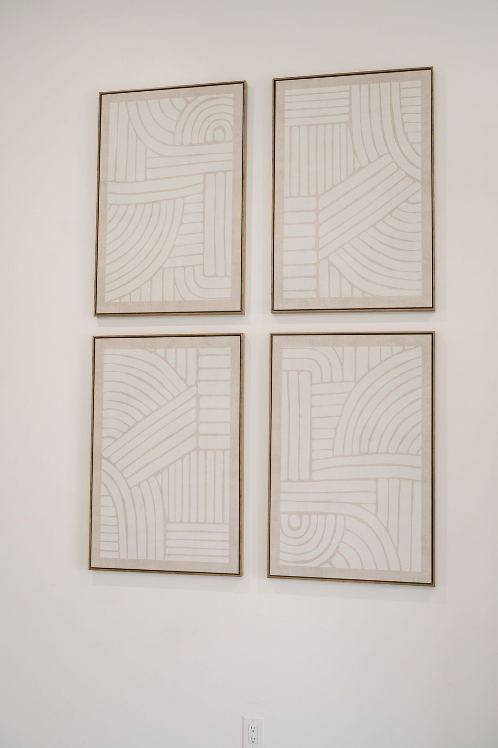Four framed abstract line art prints arranged in a grid on a white wall with geometric patterns.