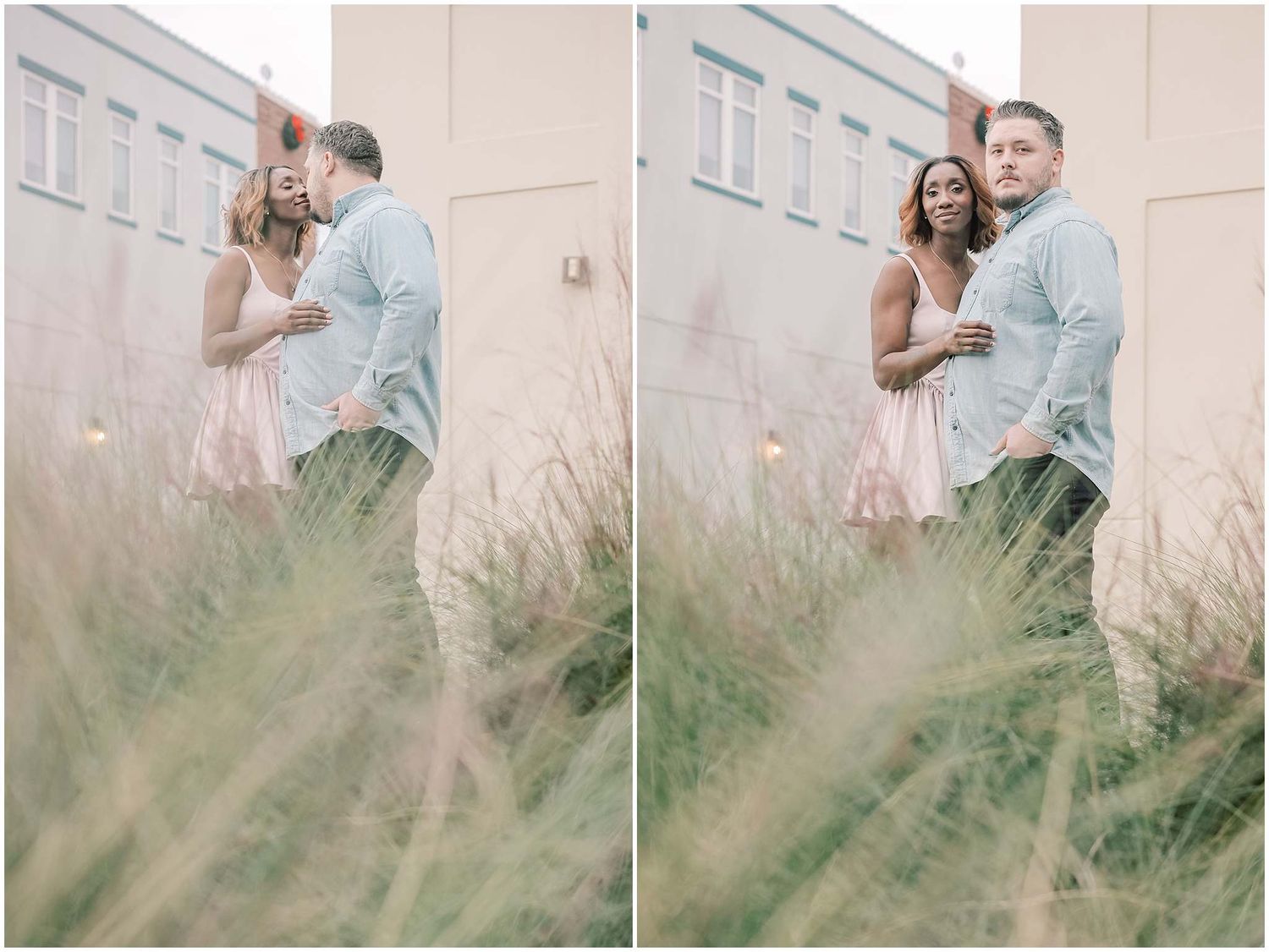 A couple shares a romantic moment in front of a light colored building with tall grass in the foreground.