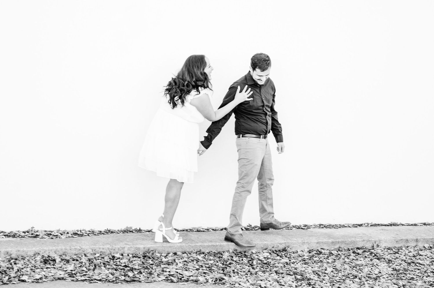 A black and white photo of a couple playfully posing outdoors.