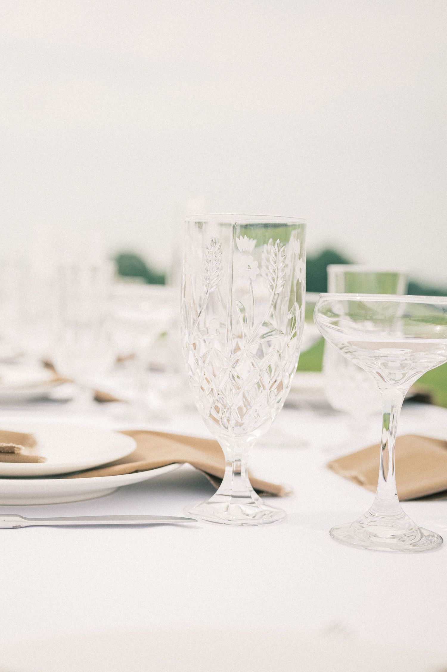 Elegant crystal wine glasses set on a white tablecloth for a formal dining event.