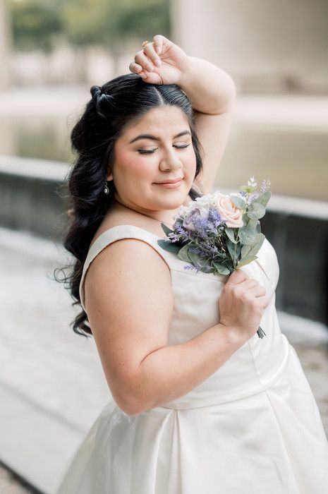 Close-up of bride with eyes closed holding pastel bouquet of roses and lavender blooms.