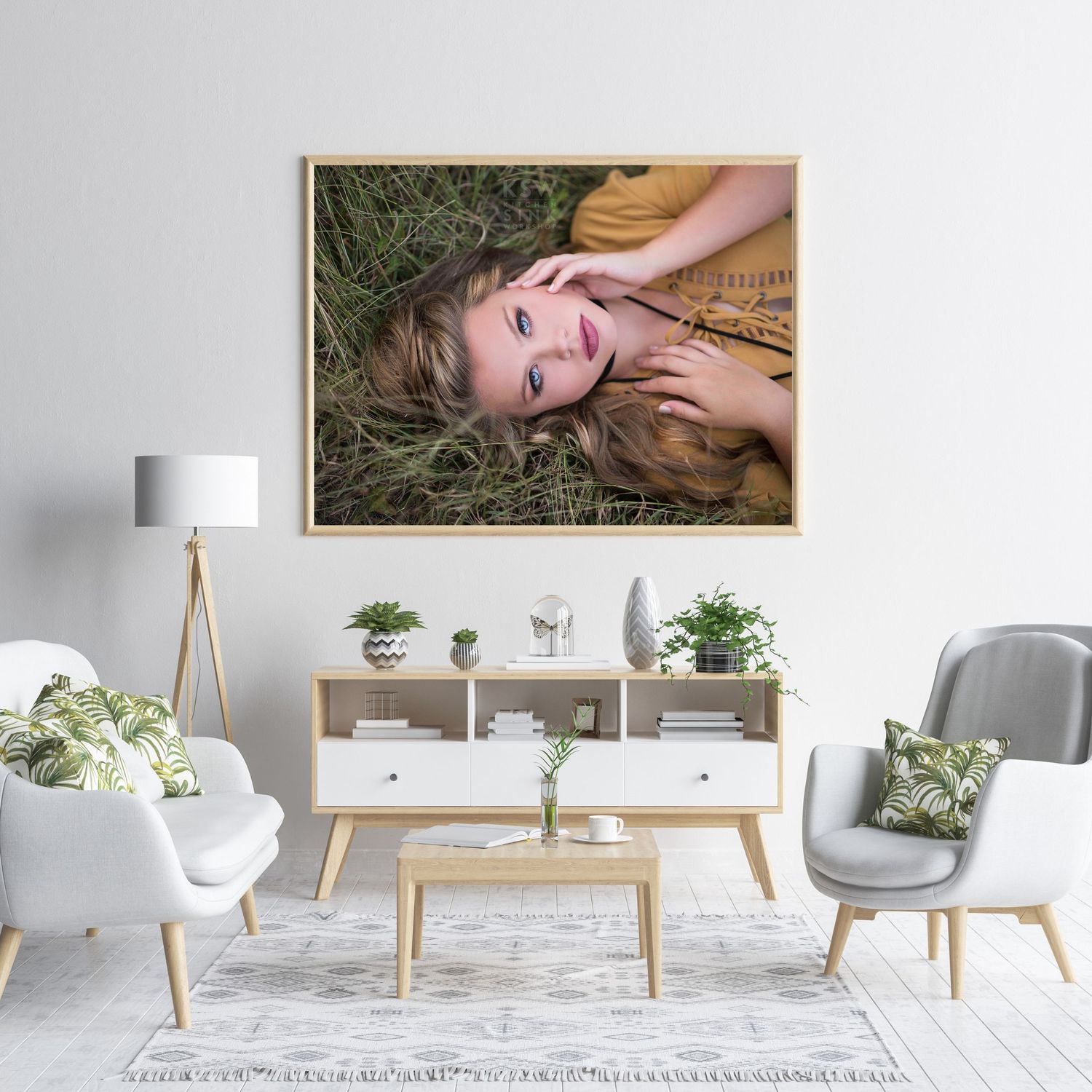 A smiling young woman lying in green grass, displayed as framed wall art in a modern living room.