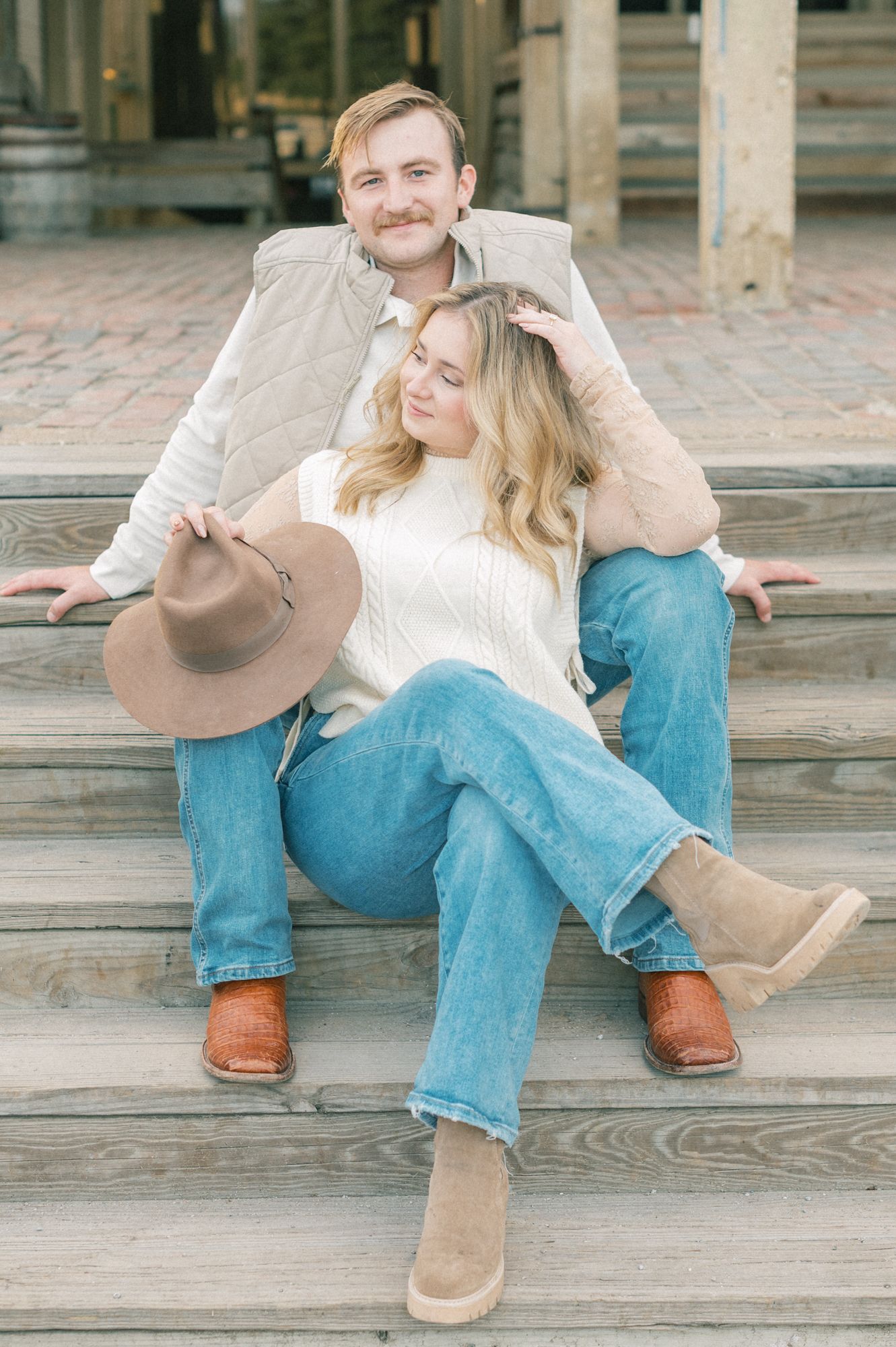 Couple in western wear embracing on wooden steps during an outdoor photo session.