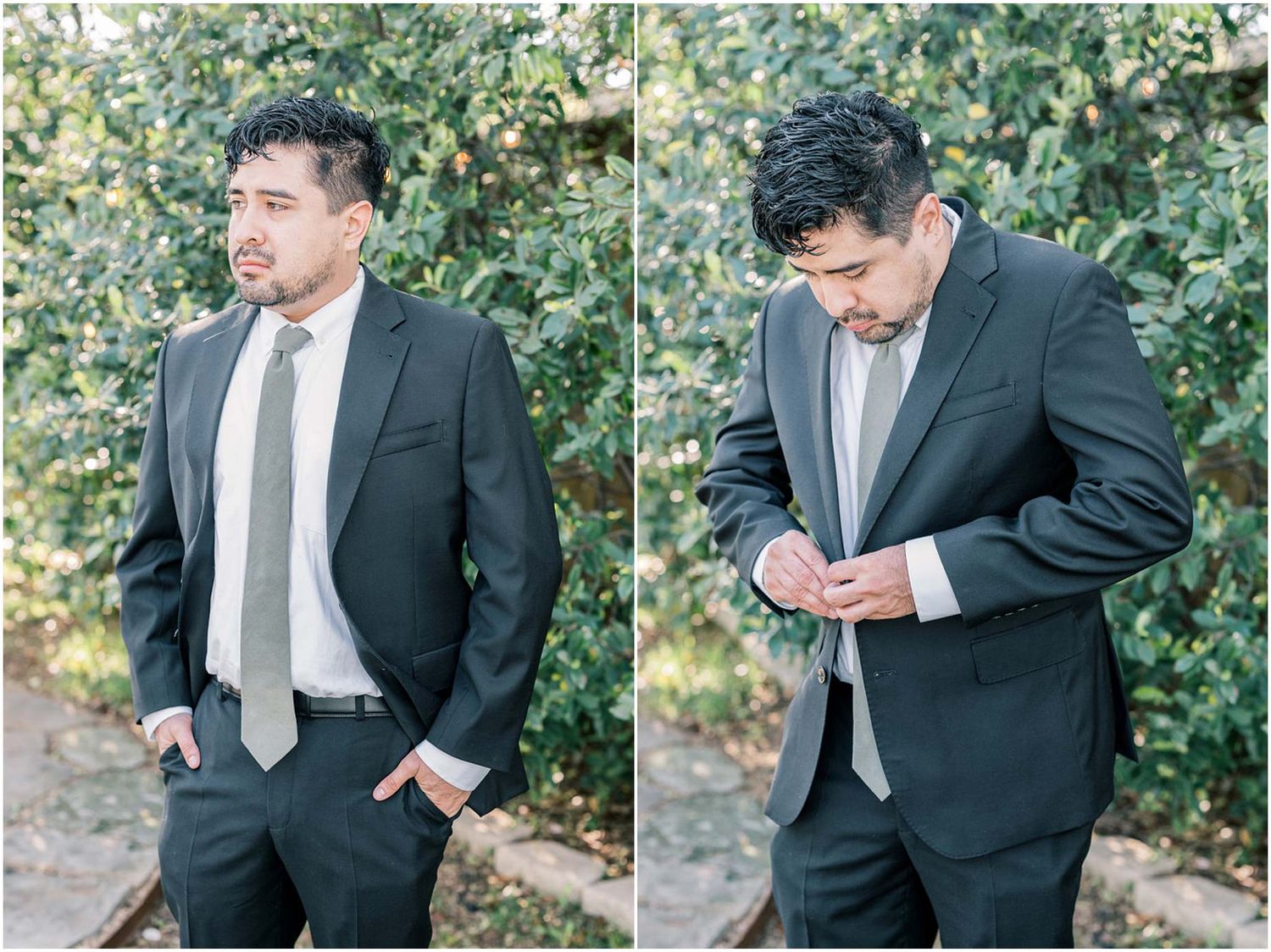A groom in a dark gray suit and light tie stands outdoors adjusting his cuffs.