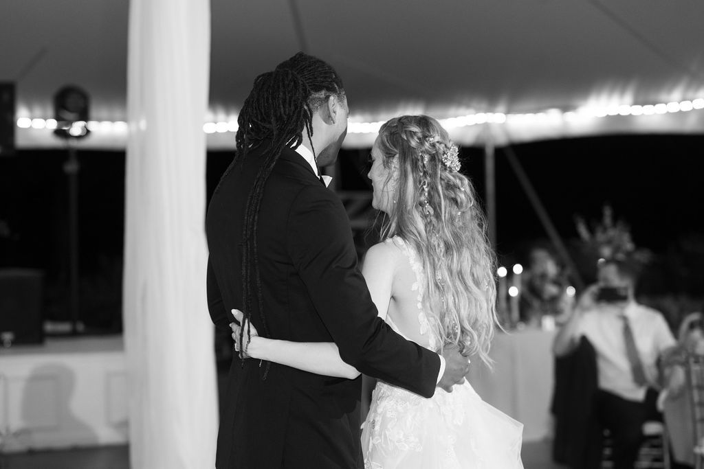 Bride and groom share first dance under tented wedding reception with soft lighting.
