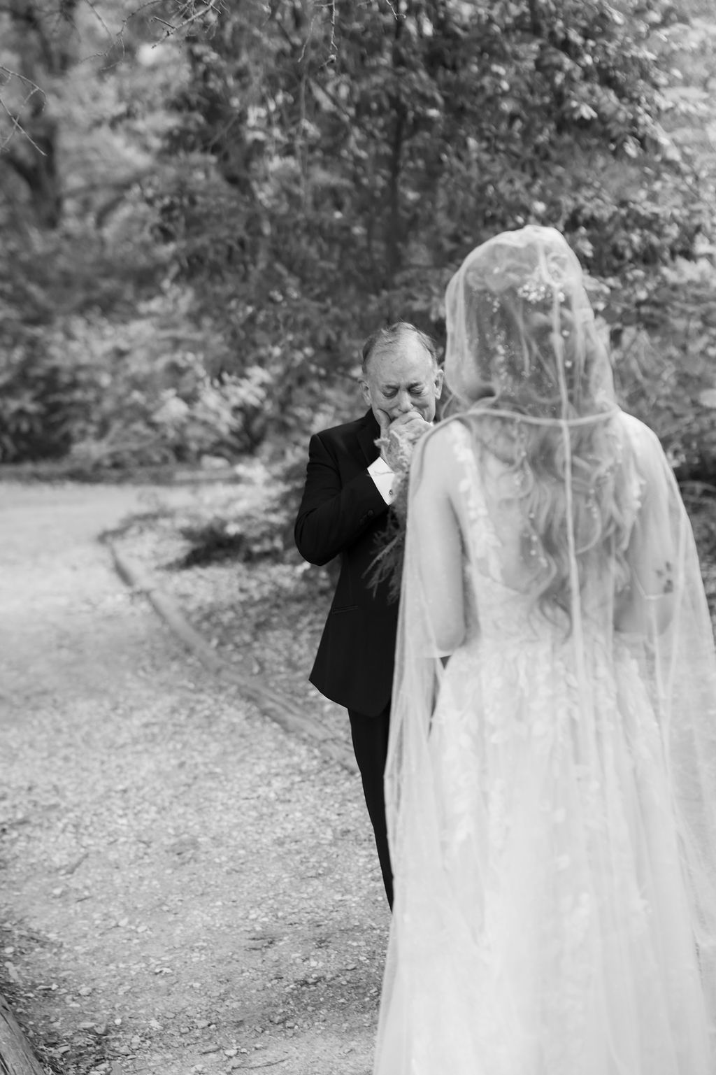 Black and white photo of emotional father seeing bride daughter for first time on wedding day outdoor first look.