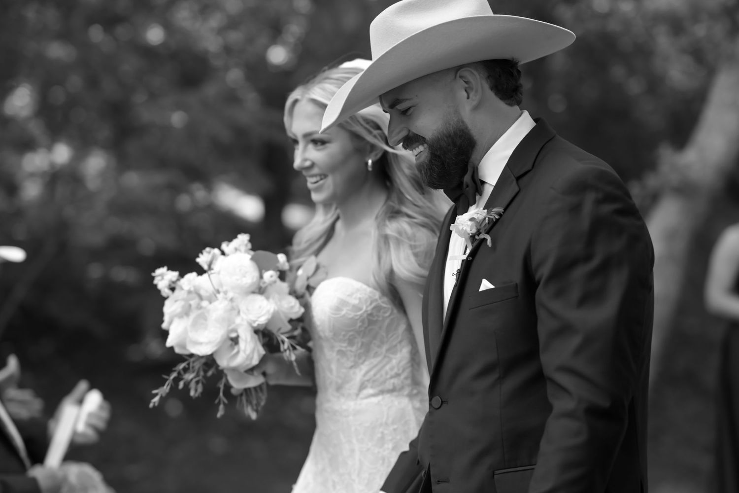 Bride and groom share a romantic moment, groom wearing a white cowboy hat and boutonniere.