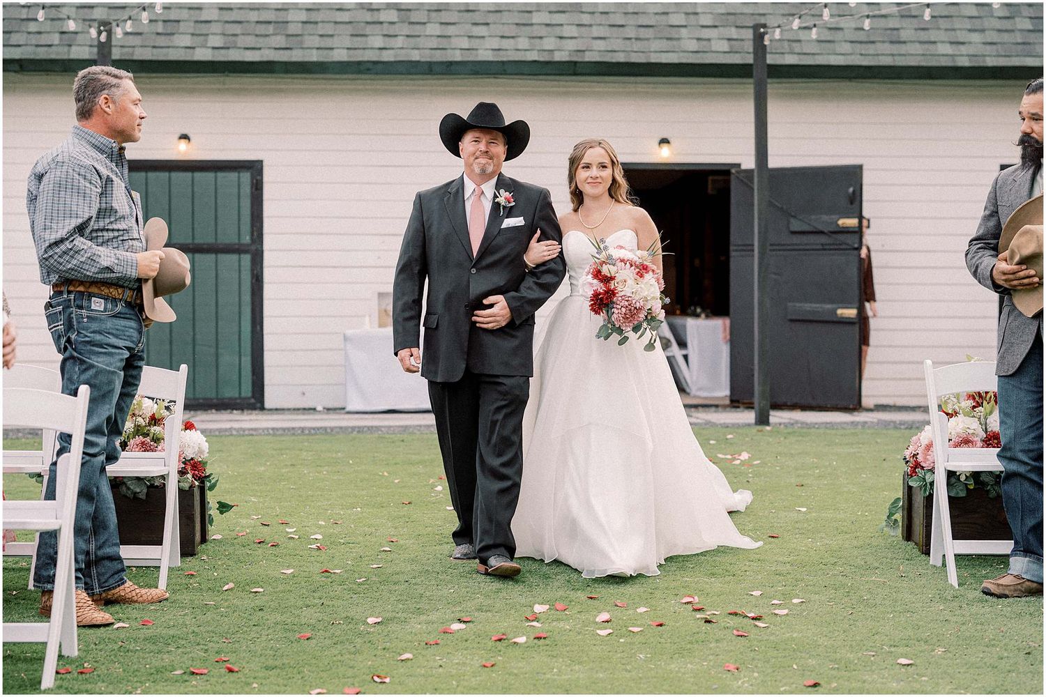 Outdoor wedding ceremony with brick building backdrop and scattered rose petals.