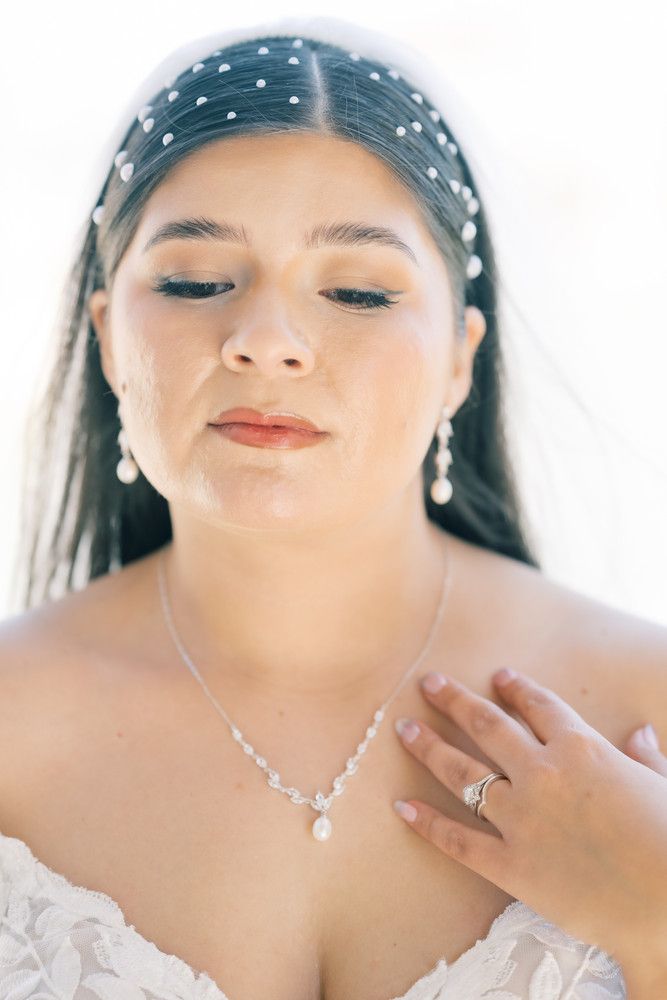 Close-up bridal portrait with delicate pearl hair accessories and soft makeup in natural light.