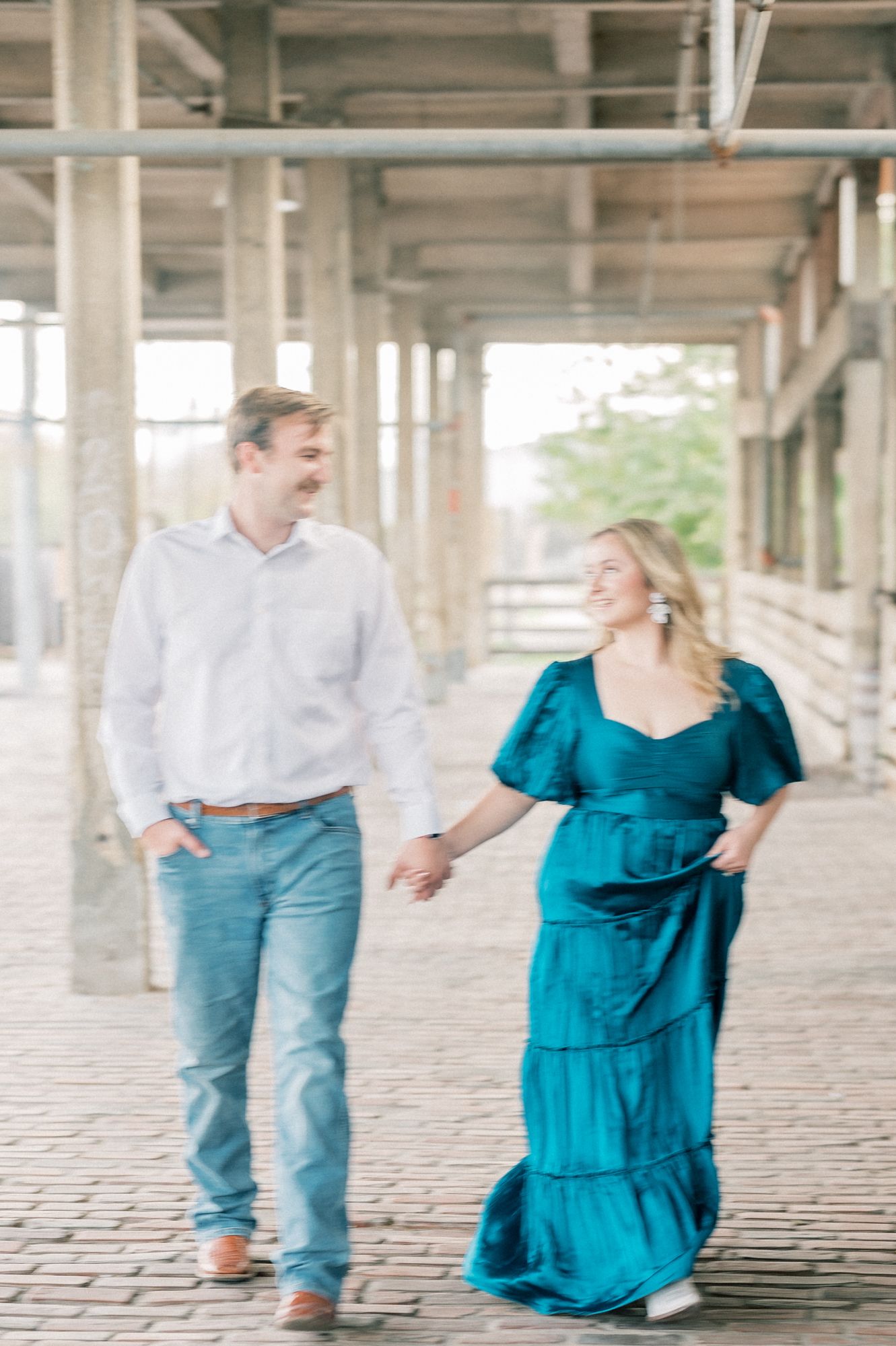 A laughing couple shares a moment while walking through an industrial-style covered pathway.