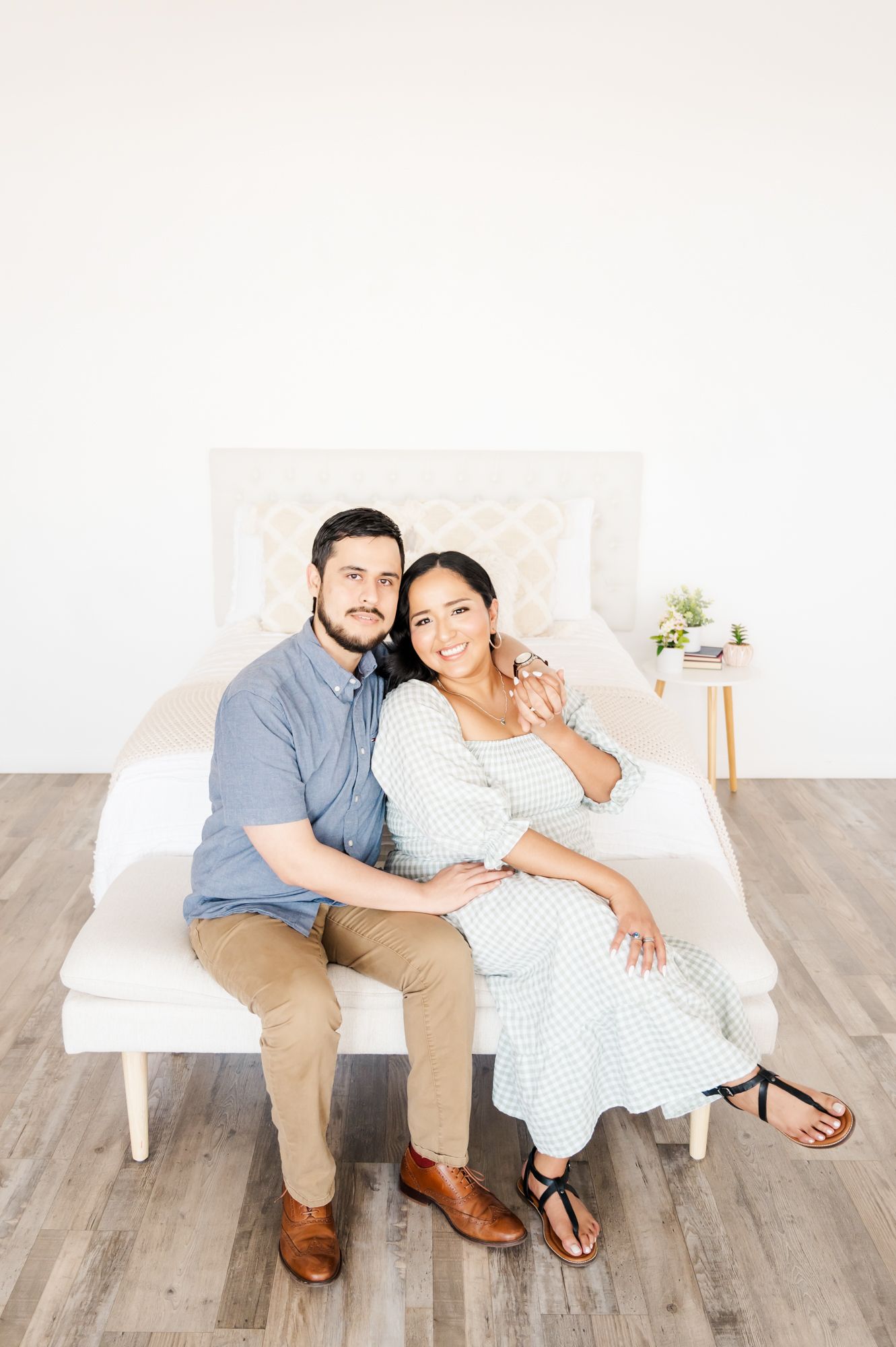 A tender moment captured on a white bench with a small side table holding flowers.