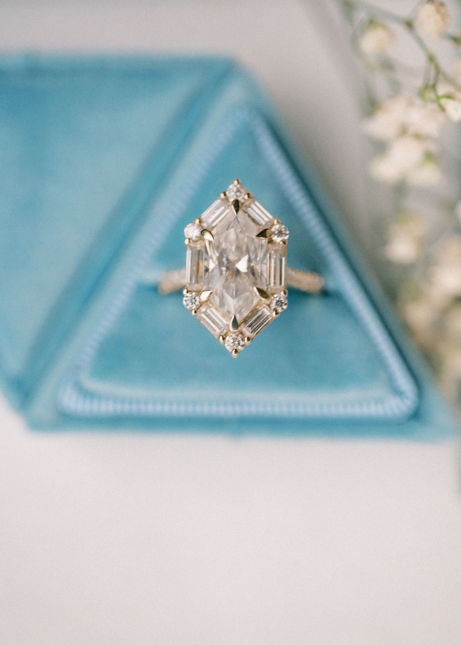 Elegant diamond engagement ring with marquise center stone and baguette accents displayed in a teal velvet ring box.