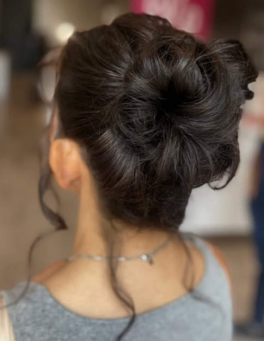 Elegant dark brown hair styled in a voluminous updo bun, viewed from behind, with loose tendrils framing the neck.