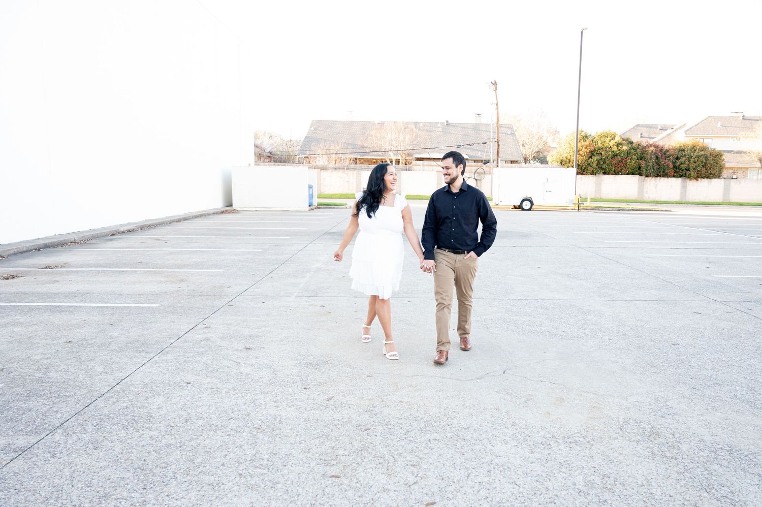 A couple walks together on a concrete pathway during an outdoor photo session at sunset.