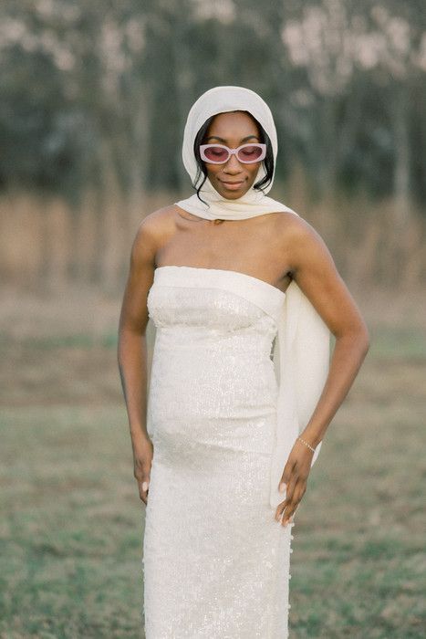 Sparkling white sequined dress glimmers in natural outdoor lighting with trees in background.
