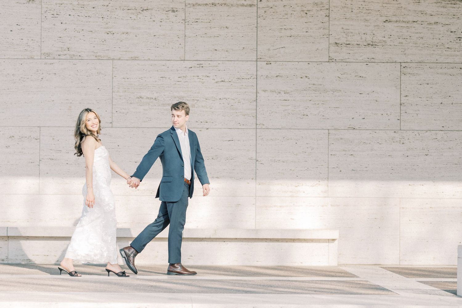 A series of four wedding photos showing a couple walking along a concrete wall in elegant attire.
