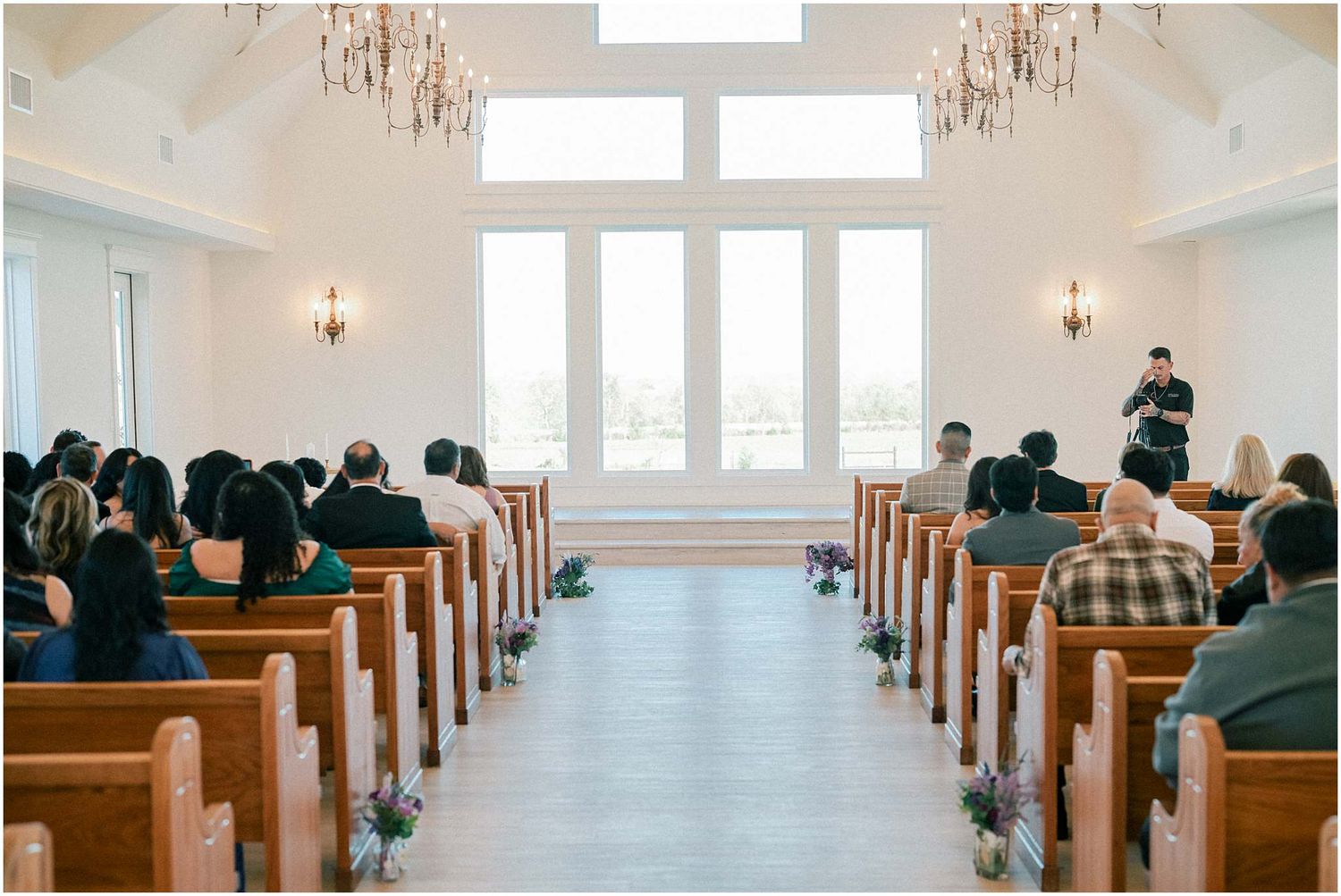 Church interior with wooden pews and bright windows during a wedding ceremony.