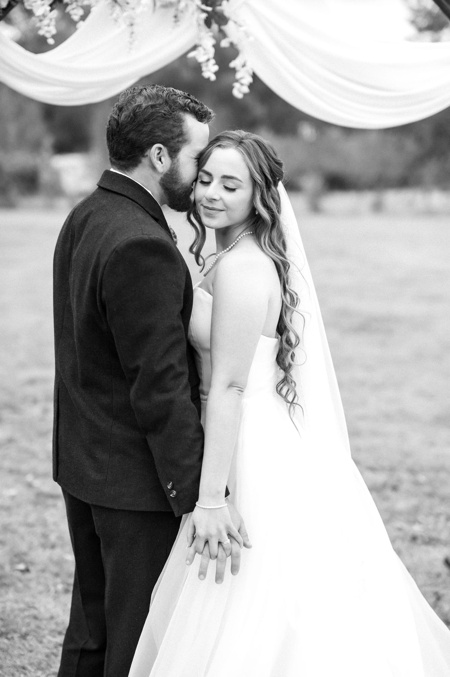 Romantic black and white wedding portraits under draped fabric decorations.