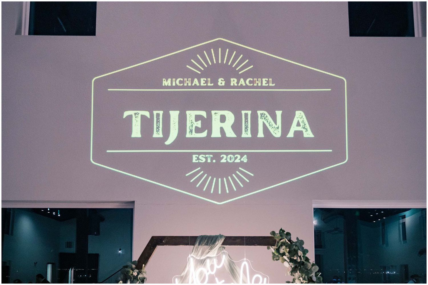 An illuminated geometric wedding sign displaying 'Tijerina' against a dark wall with modern lighting.