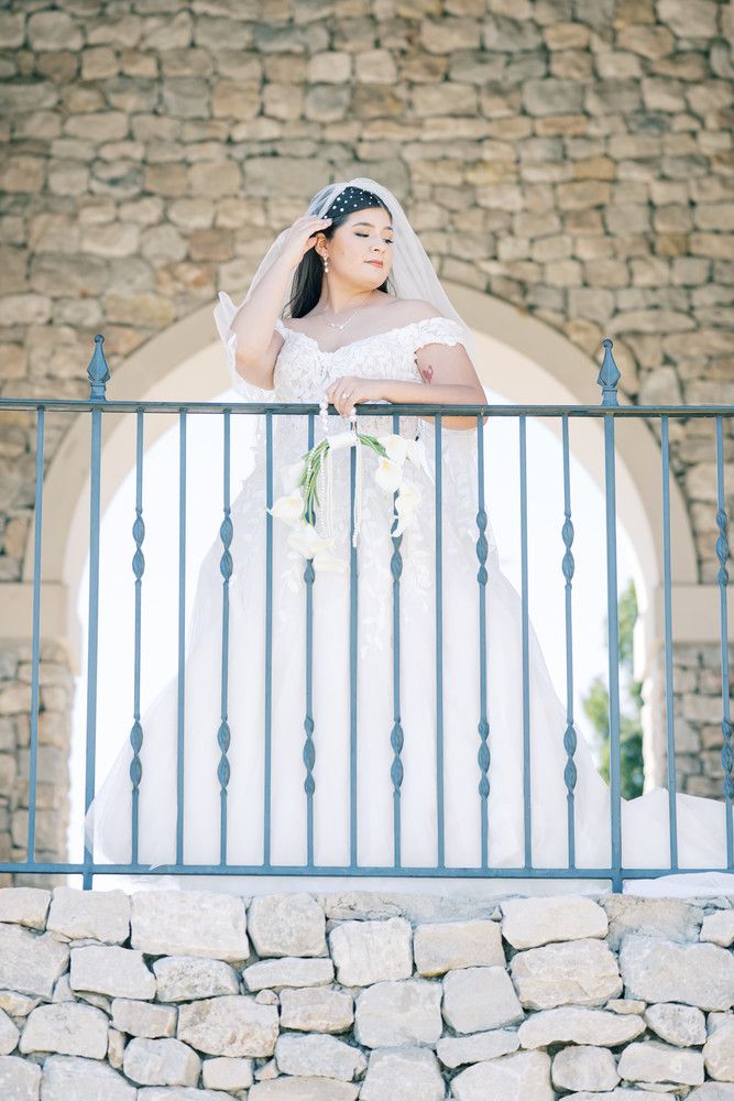 Romantic bridal portrait on a stone balcony with ornate iron railings and architectural details.