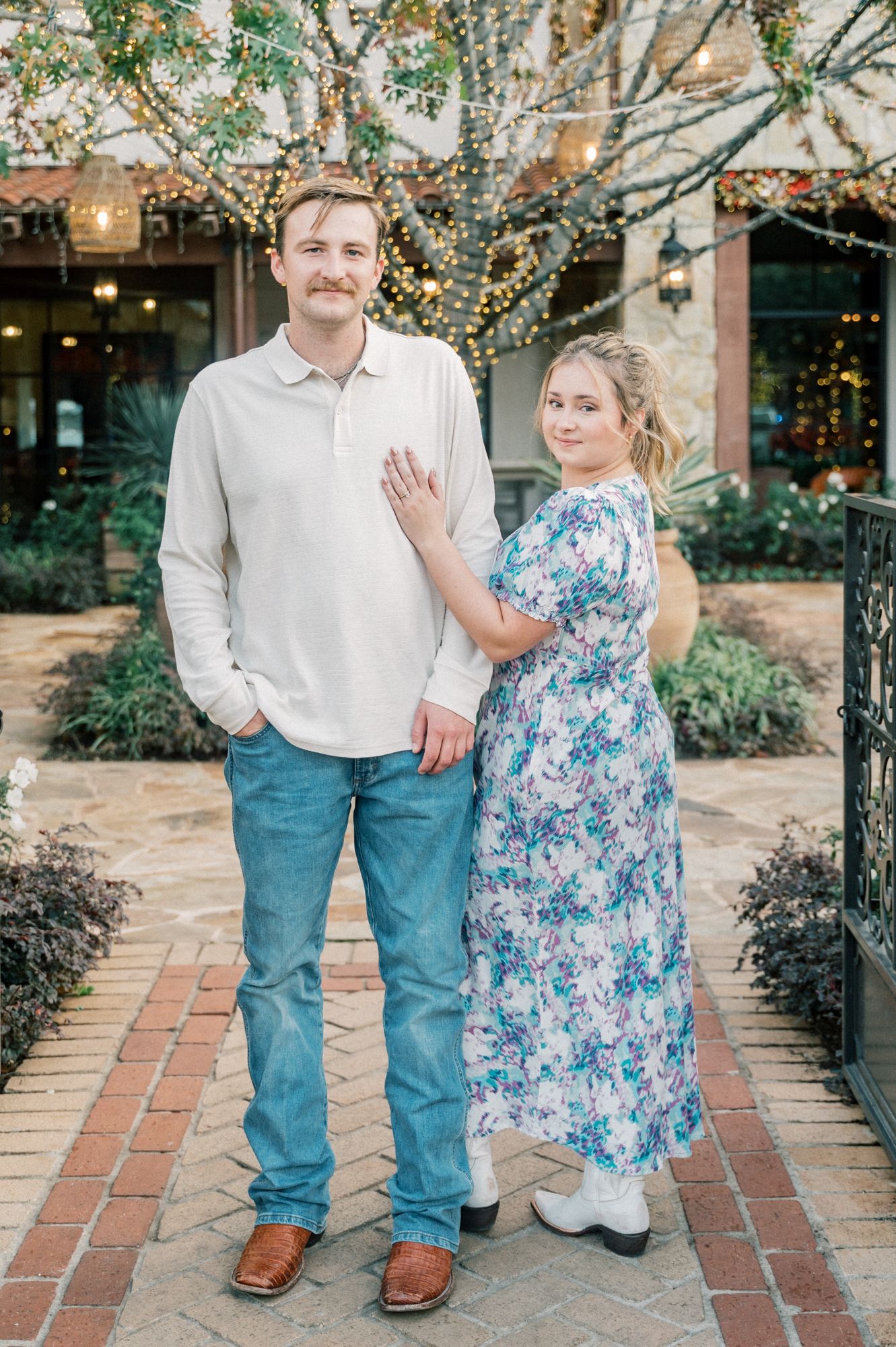 A romantic moment captured on a garden path with string lights and stone walls.
