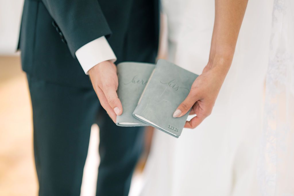 Bride and groom exchanging wedding vow booklets during elegant ceremony.
